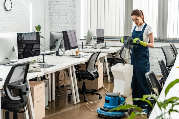 Jeune laveuse plus propre dans un bureau à aire ouverte avec machine de nettoyage — Photo de stock