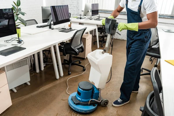 Partial view of african amercan cleaner washing floor with cleaning machine — Stock Photo