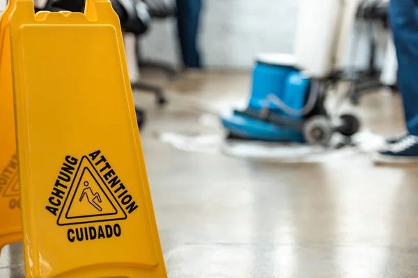 Foco seletivo do sinal de cautela piso molhado perto de piso de lavagem mais limpo com máquina de limpeza — Fotografia de Stock