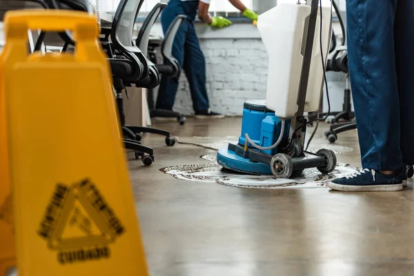 Ausgeschnittener Blick auf sauberen Waschboden mit Putzmaschine in der Nähe des Kollegen — Stockfoto