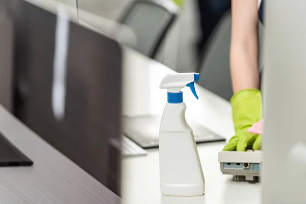 Cropped view of cleaner wiping phone near detergent spray — Stock Photo