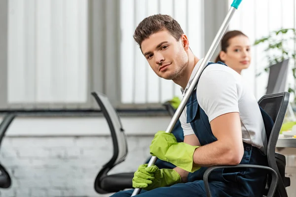 Handsome cleaner sitting in office chair near attractive colleague — Stock Photo