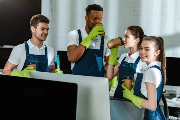 Happy multicultural cleaners drinking coffee to go in office — Stock Photo