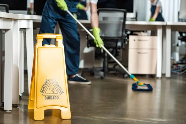 Recortado de piso de lavado más limpio con fregona cerca de señal de precaución piso mojado - foto de stock