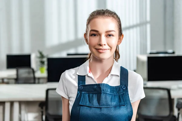 Attractive young cleaner in overalls smiling at camera — Stock Photo