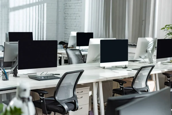 Modern open space office with computer monitors on white desks — Stock Photo