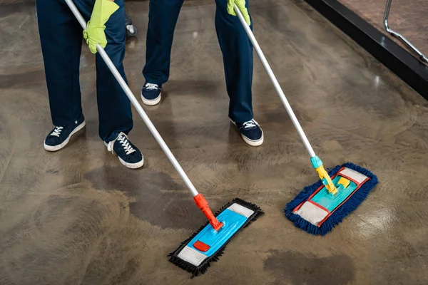 Vue recadrée de deux nettoyants plancher de lavage avec des vadrouilles — Photo de stock