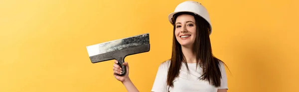 Plano panorámico de manitas sonrientes sosteniendo paleta sobre fondo amarillo - foto de stock