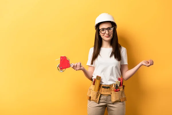 Lächelnde Handarbeiterin mit Klebebandspender, die in die Kamera auf gelbem Hintergrund blickt — Stockfoto