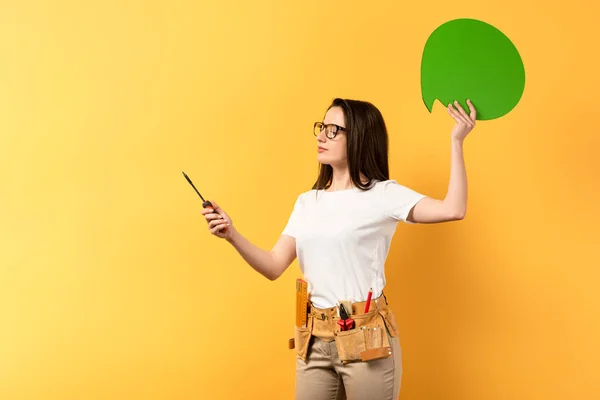 Reparadora segurando pensamento bolha e chave de fenda no fundo amarelo — Fotografia de Stock