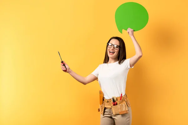 Riparatrice sorridente che tiene cacciavite e bolla pensiero su sfondo giallo — Foto stock