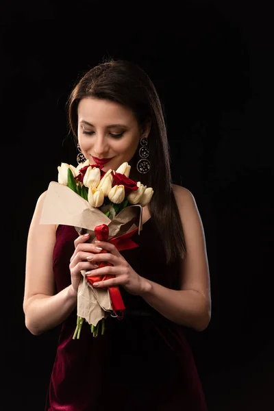 Sonriente mujer en vestido aroma ramo aislado en negro - foto de stock