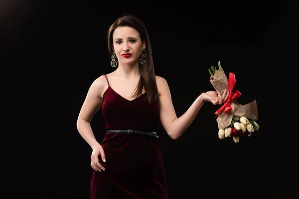 Enttäuschte Frau im Kleid mit Blumenstrauß auf Schwarz — Stockfoto