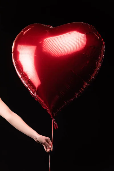 Vista recortada de la mujer sosteniendo globo en forma de corazón en 14 febrero aislado en negro - foto de stock