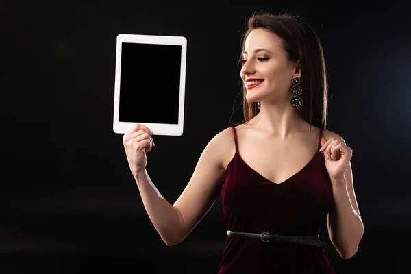 Femme souriante en robe tenant tablette numérique sur fond noir — Photo de stock