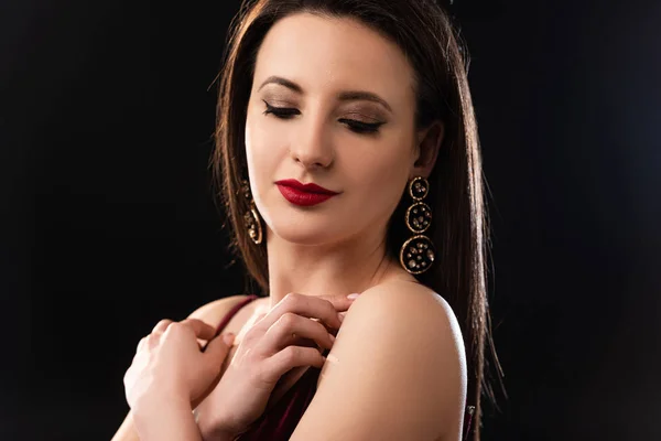 Attractive woman with earrings looking down on black background — Stock Photo