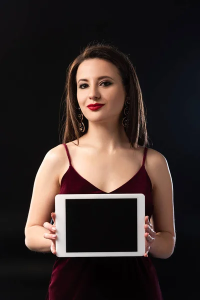 Smiling woman in dress holding digital tablet on black background — Stock Photo