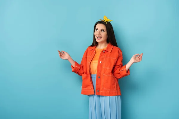 Mujer sonriente con mariposa de papel en la cabeza sobre fondo azul - foto de stock