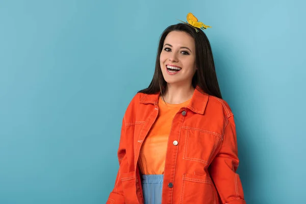 Mulher sorridente com borboleta de papel na cabeça no fundo azul — Fotografia de Stock