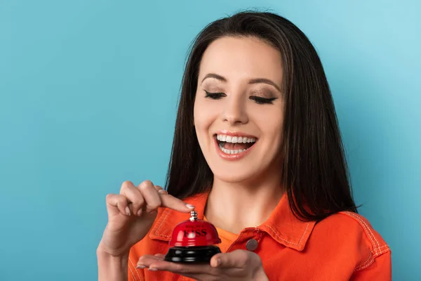 Femme souriante sonnant dans la cloche de service sur fond bleu — Photo de stock