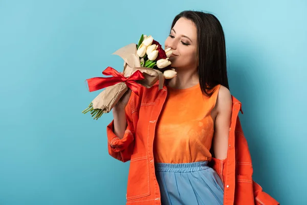 Donna sorridente in giacca profumato bouquet su sfondo blu — Foto stock