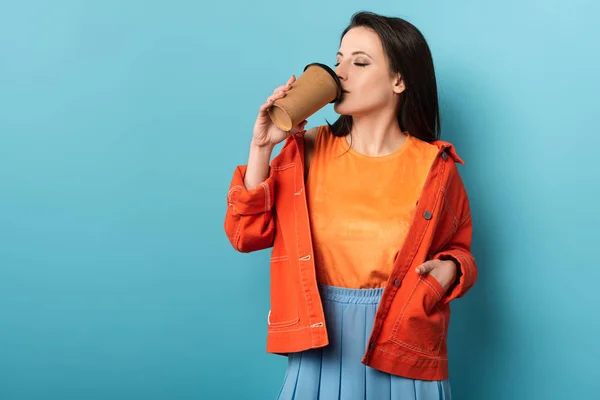 Mulher bebendo café de copo de papel no fundo azul — Fotografia de Stock