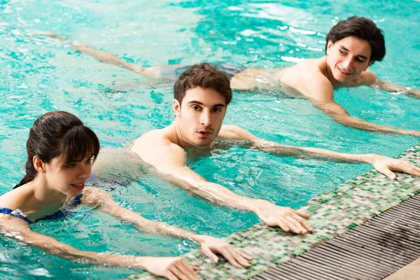 Молодые люди занимаются в бассейне во время водной аэробики — стоковое фото