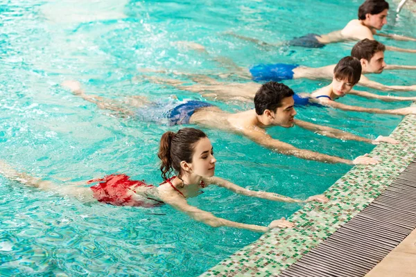 Grupo de jóvenes entrenando juntos en la piscina - foto de stock