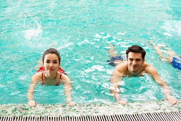 Lächelnder Mann und Frau trainieren gemeinsam im Schwimmbad — Stockfoto