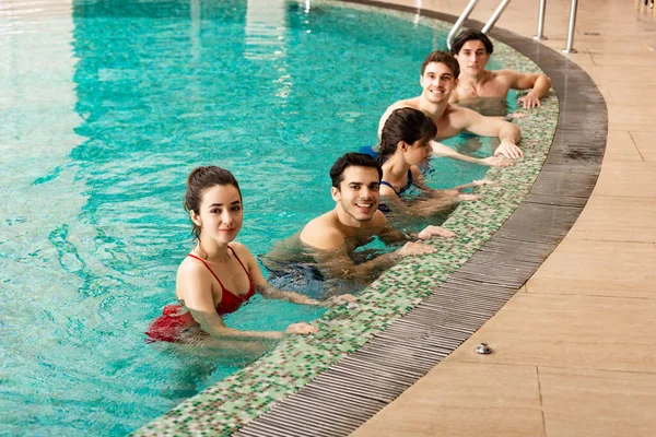 Gente sorridente che guarda la macchina fotografica mentre si allena in piscina — Foto stock