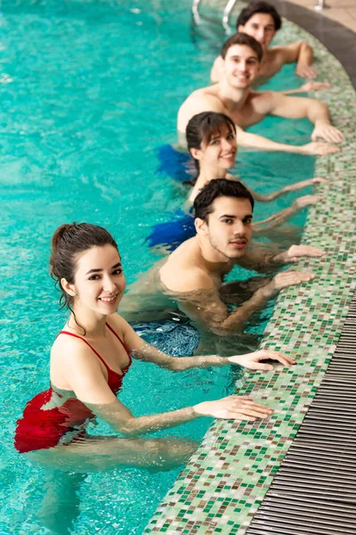 Selective focus of group of young people smiling at camera in swimming pool — Stock Photo