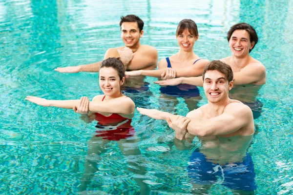 Giovani che sorridono alla telecamera mentre si allenano in piscina — Foto stock