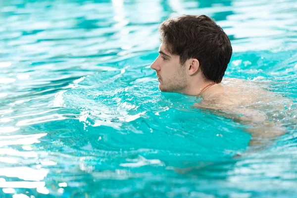 Vista lateral del joven nadando en la piscina - foto de stock