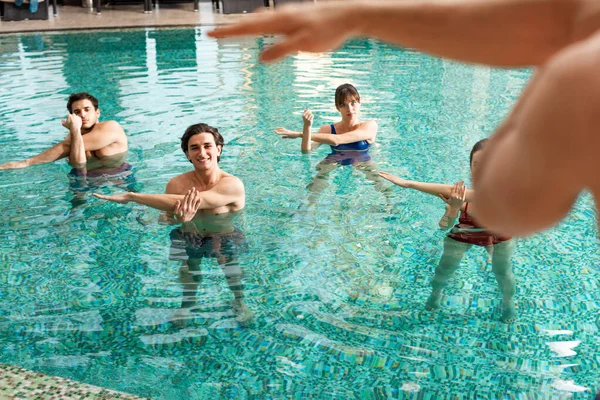 Enfoque selectivo del formador que muestra el ejercicio al grupo de jóvenes en la piscina - foto de stock