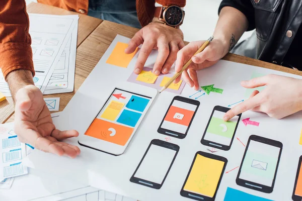 Zugeschnittene Ansicht der Entwickler kreatives User Experience Design der mobilen Website mit Layouts auf dem Tisch isoliert auf grau — Stockfoto