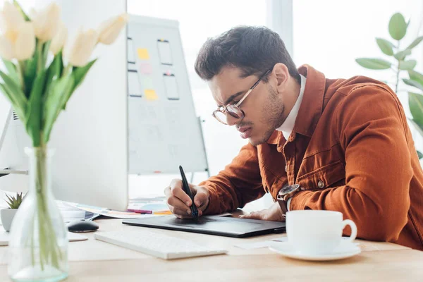 Side view of ux designer working with computer and graphics tablet at table in office — Stock Photo