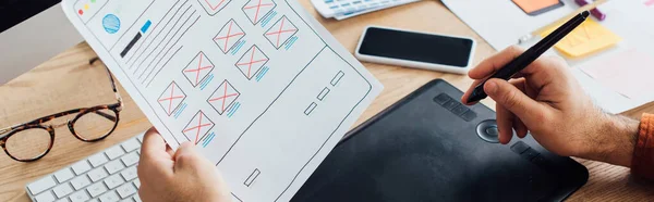 Vue recadrée du concepteur en utilisant une tablette graphique tout en planifiant la conception de l'expérience utilisateur du site Web à la table, vue panoramique — Photo de stock