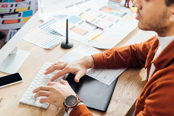 Vista recortada del desarrollador utilizando la computadora cerca de diseños de diseño ux en la mesa - foto de stock