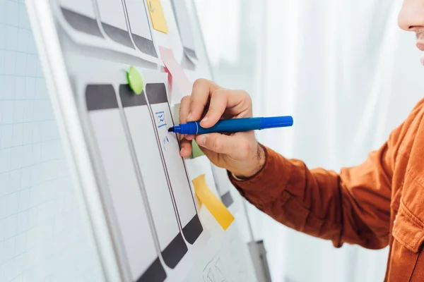 Cropped view of developer with marker planning ux design of mobile website with templates on whiteboard — Stock Photo