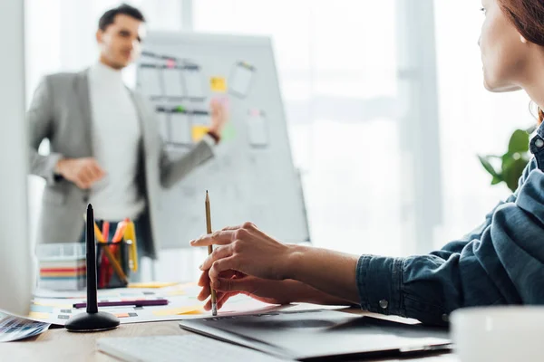 Enfoque selectivo del diseñador ux mirando colega cerca de pizarra en la oficina - foto de stock