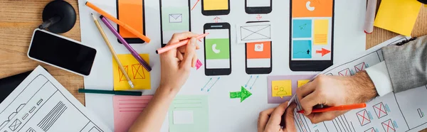 Vue du dessus des concepteurs interface d'application créative pour la conception de l'expérience utilisateur près des mises en page et smartphone sur la table, vue panoramique — Photo de stock