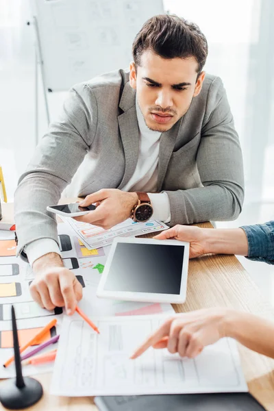 Selective focus of ux designer pointing on template of website near colleague in office — Stock Photo