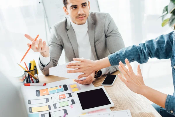 Selective focus of ux designer showing stop gesture to colleague near web layouts on table — Stock Photo