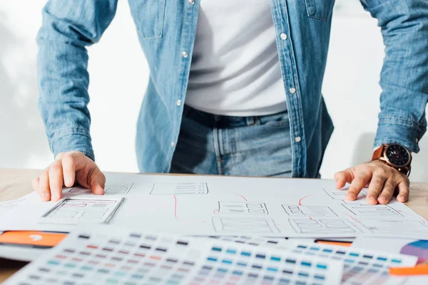 Cropped view of ux designer using app sketches and color palettes on table in office — Stock Photo