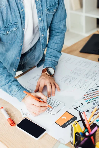 Cropped view of ux developer sketching mobile interface near smartphone on table — Stock Photo