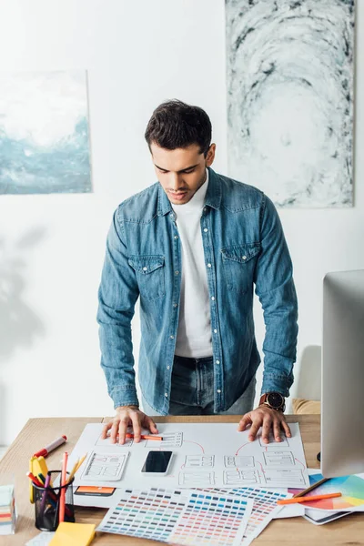 Handsome ux interfaz de la aplicación de planificación de diseño cerca de teléfonos inteligentes y paletas de colores en la mesa — Stock Photo