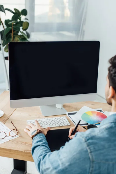 Back view of ux designer using graphics tablet and computer near sketches on table — Stock Photo