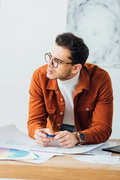 Pensive ux developer planning project near color circles and sketches of user experience design on table — Stock Photo