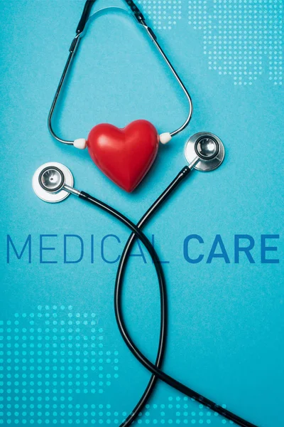Top view of decorative red heart with black stethoscope on blue background, medical care illustration — Stock Photo