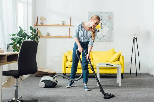 Lächelnde Frau putzt Teppich mit Staubsauger im Wohnzimmer — Stockfoto